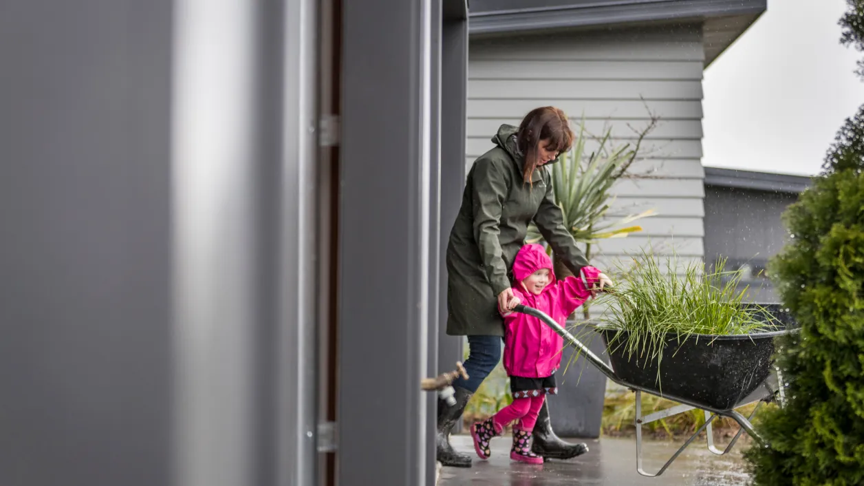 Family standing beside a home with Hardie plank and panel siding mix