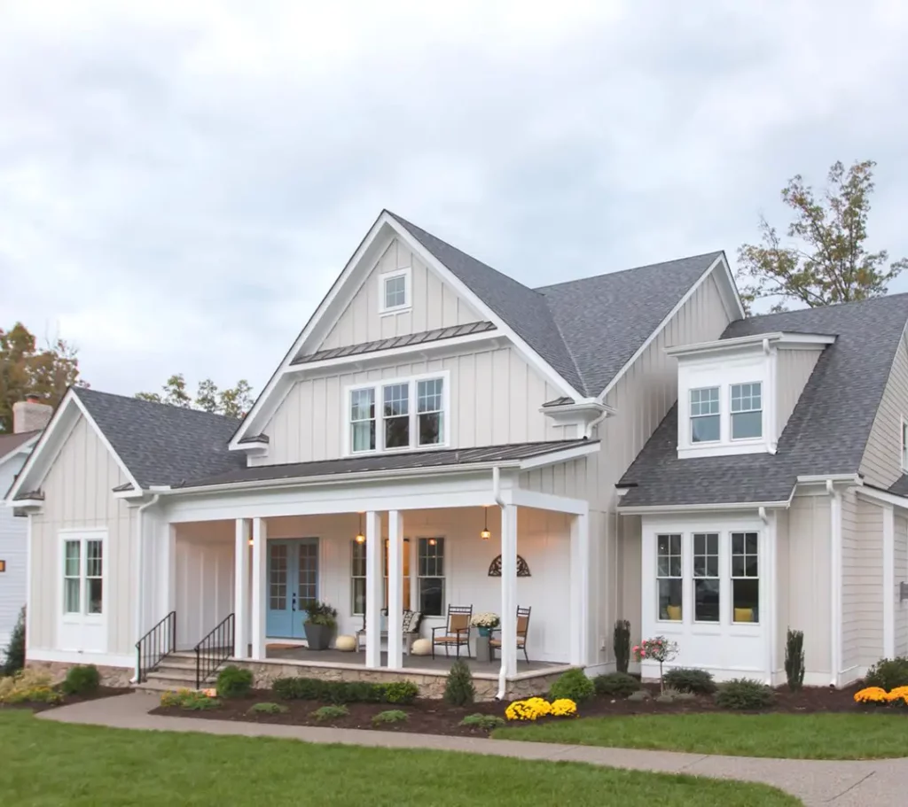 Modern farmhouse-style home with pitched roof, white siding, and a welcoming front porch, perfect for roofing and siding upgrades.