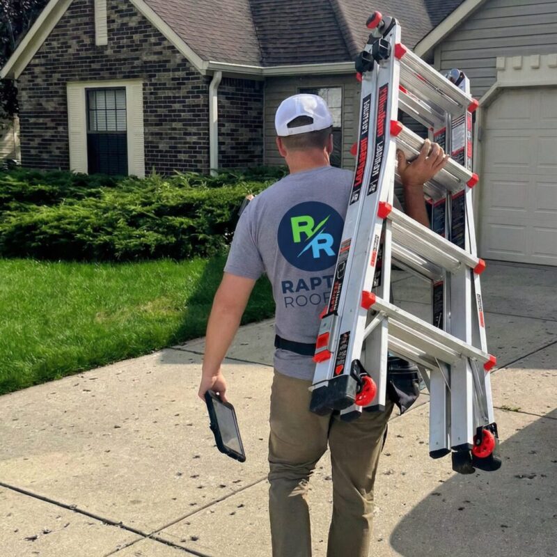 Raptor Roofing inspector carrying a ladder and tablet toward a Central Indiana home