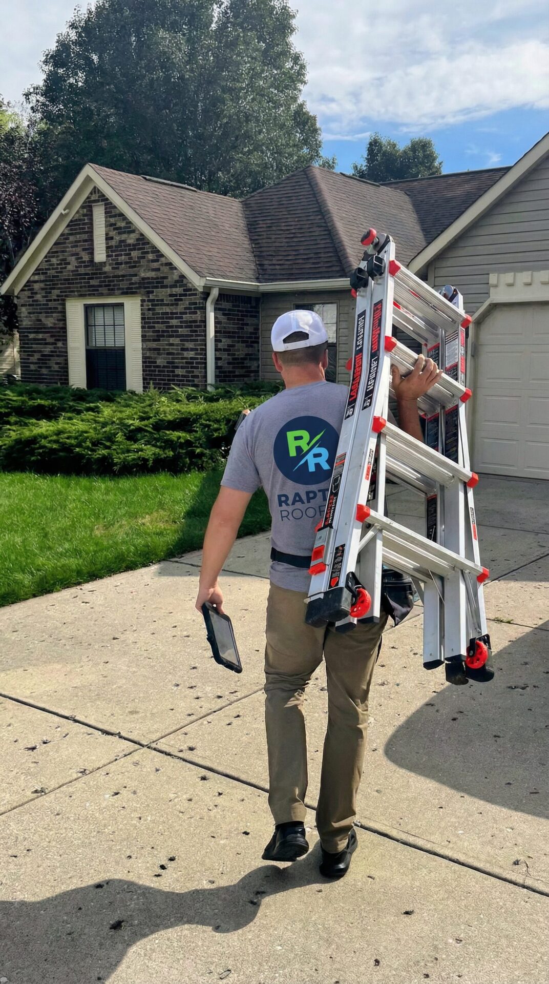 Raptor Roofing inspector carrying a ladder and tablet toward a Central Indiana home
