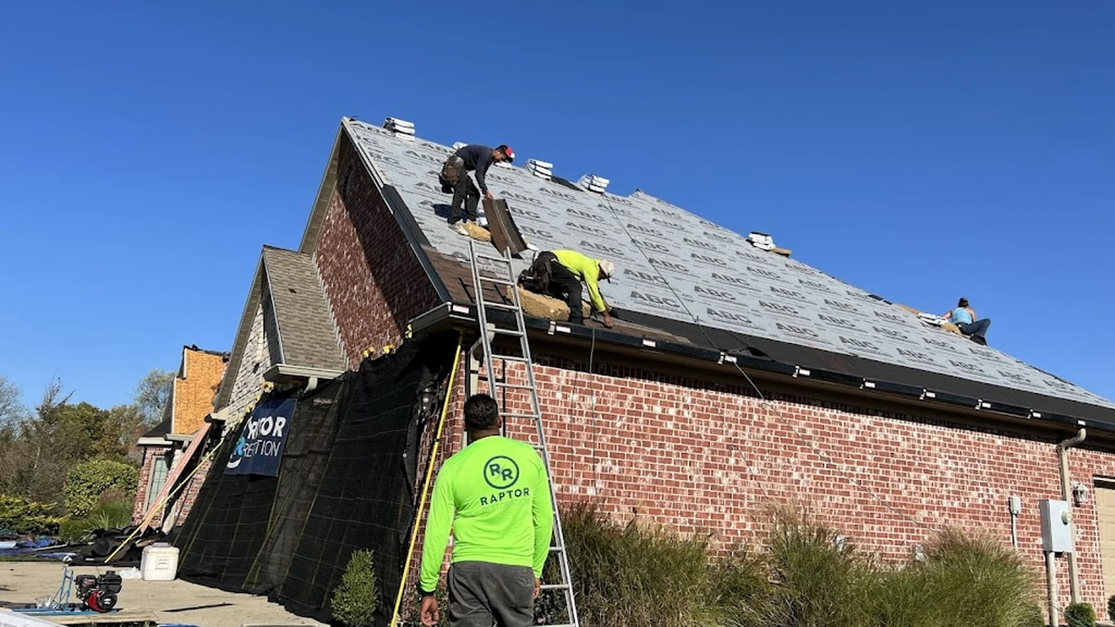 Raptor Roofing crew installing underlayment during a residential roof replacement