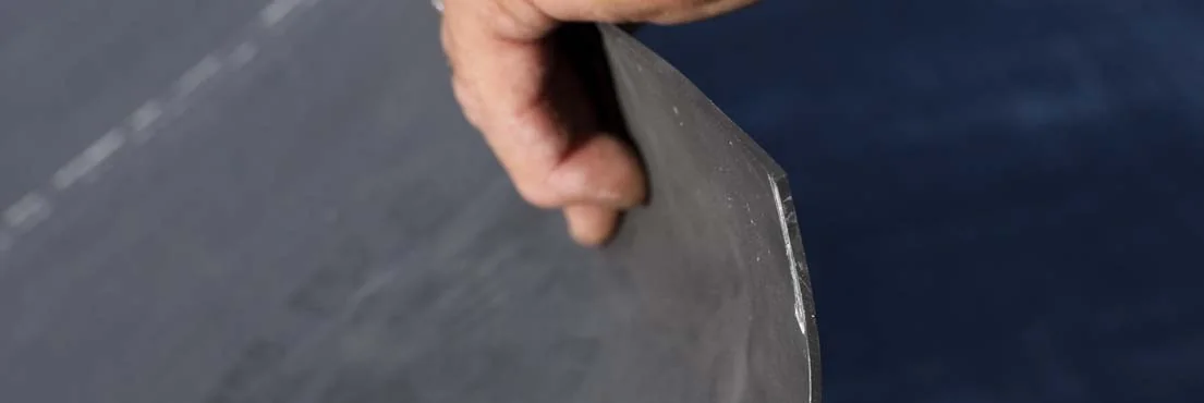 Close-up of black EPDM rubber roofing membrane held for inspection