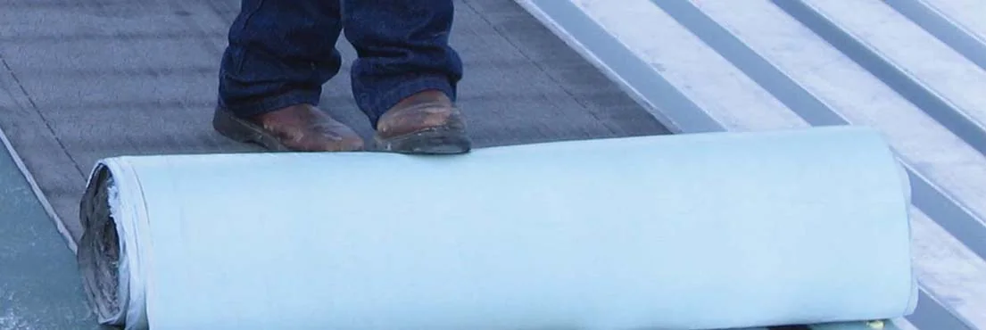 Modified bitumen base sheet being rolled across a low slope commercial roof