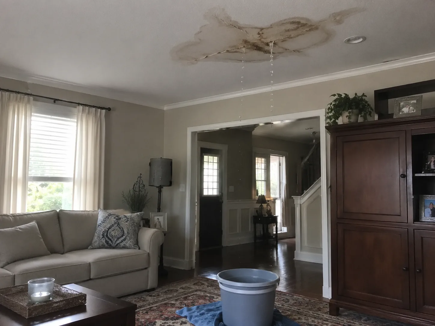 Active ceiling leak with water dripping into a bucket inside a Noblesville area home