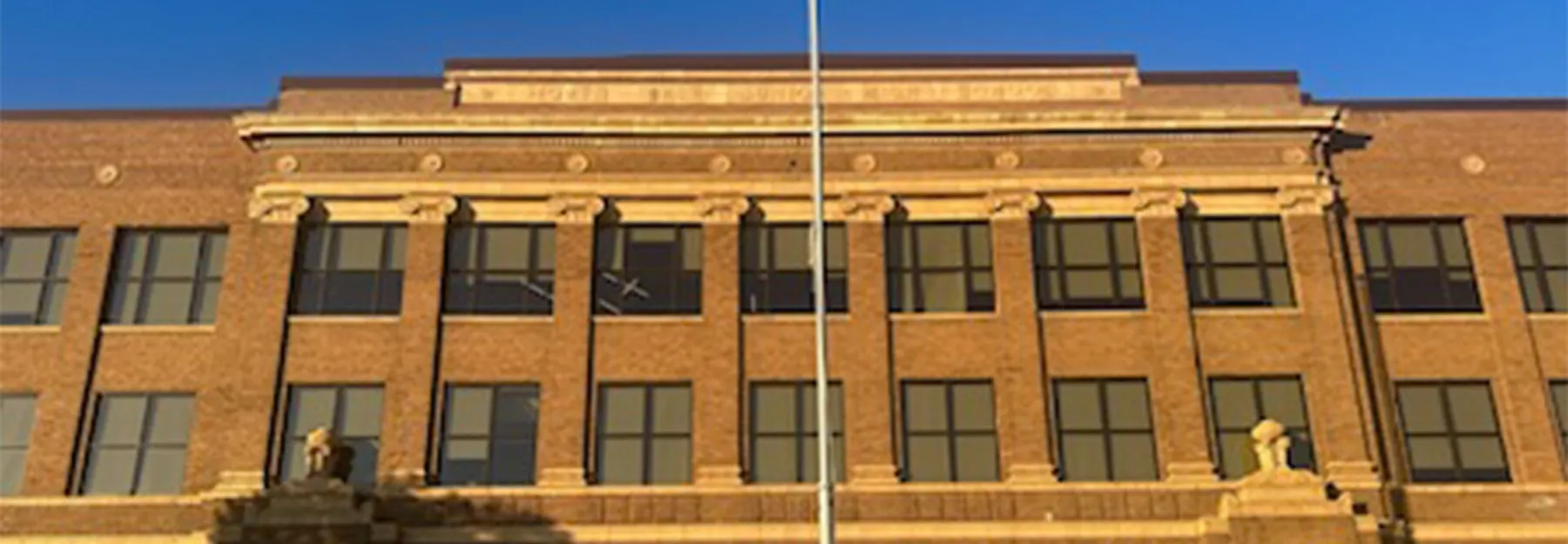 Brick school building with tall windows and architectural stone details