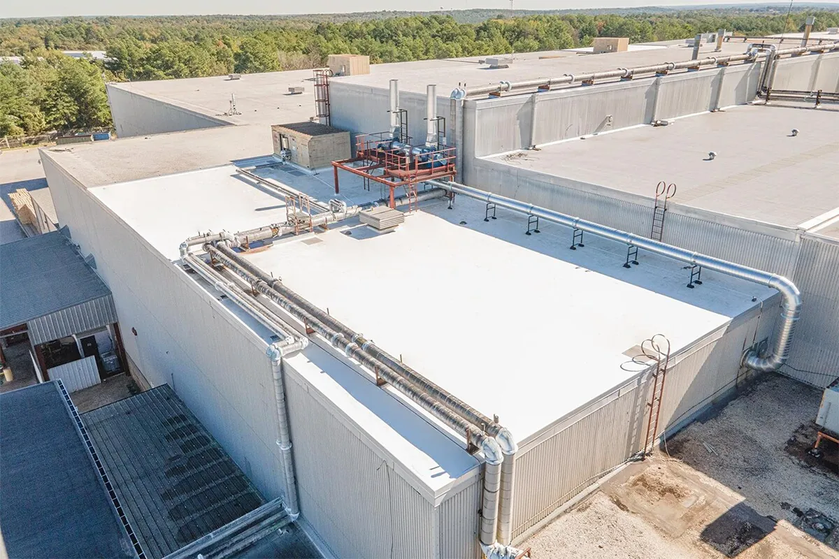 Completed white TPO roof with equipment curbs and raised roof sections