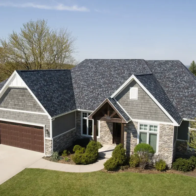 Gray dimensional shingle roof on a stone and siding home with multiple gables