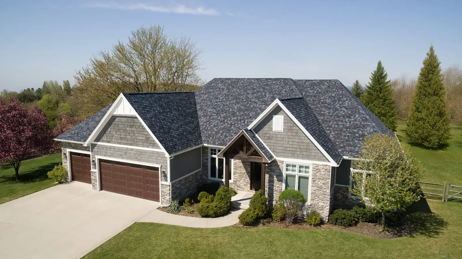 Gray dimensional shingle roof on a stone and siding home with multiple gables