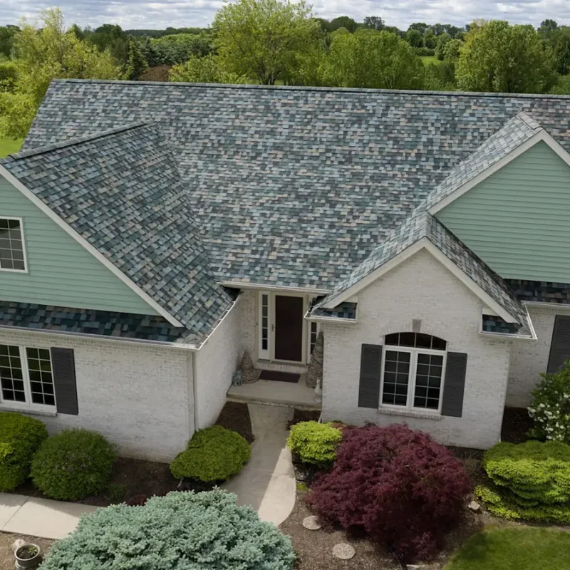 Green-gray dimensional shingle roof paired with sage siding and light stone