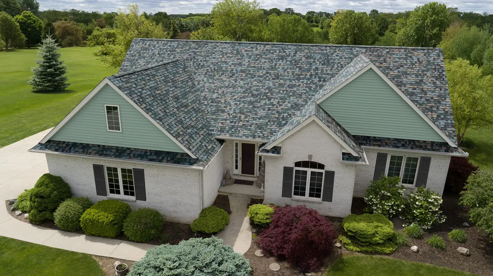 Green-gray dimensional shingle roof paired with sage siding and light stone