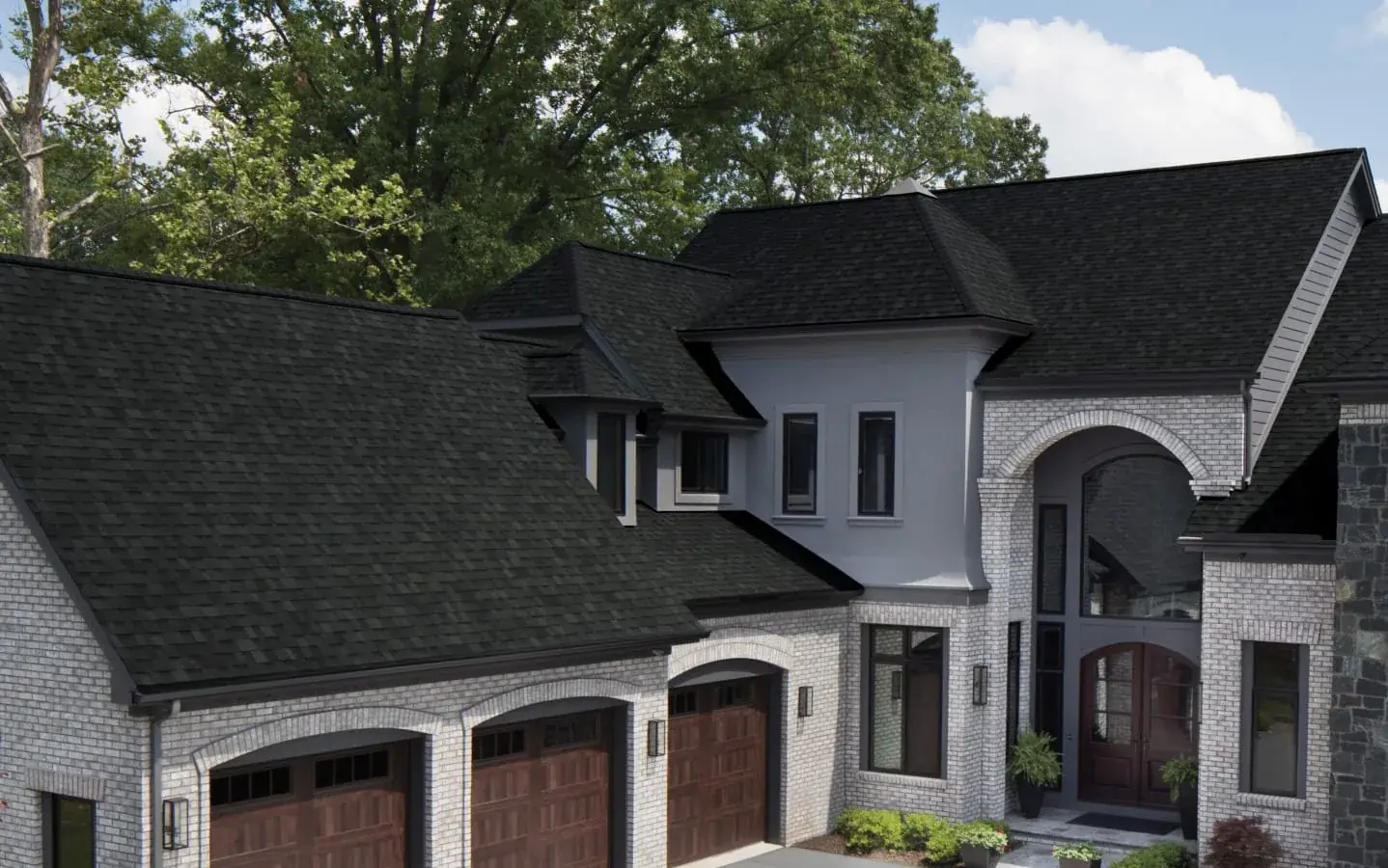 Black dimensional shingles across the gables of a light brick home