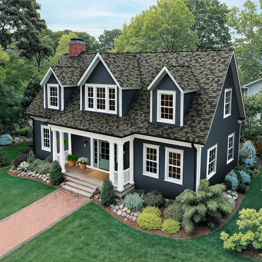 Dark cottage with dormers, white trim, and a green-gray dimensional shingle roof